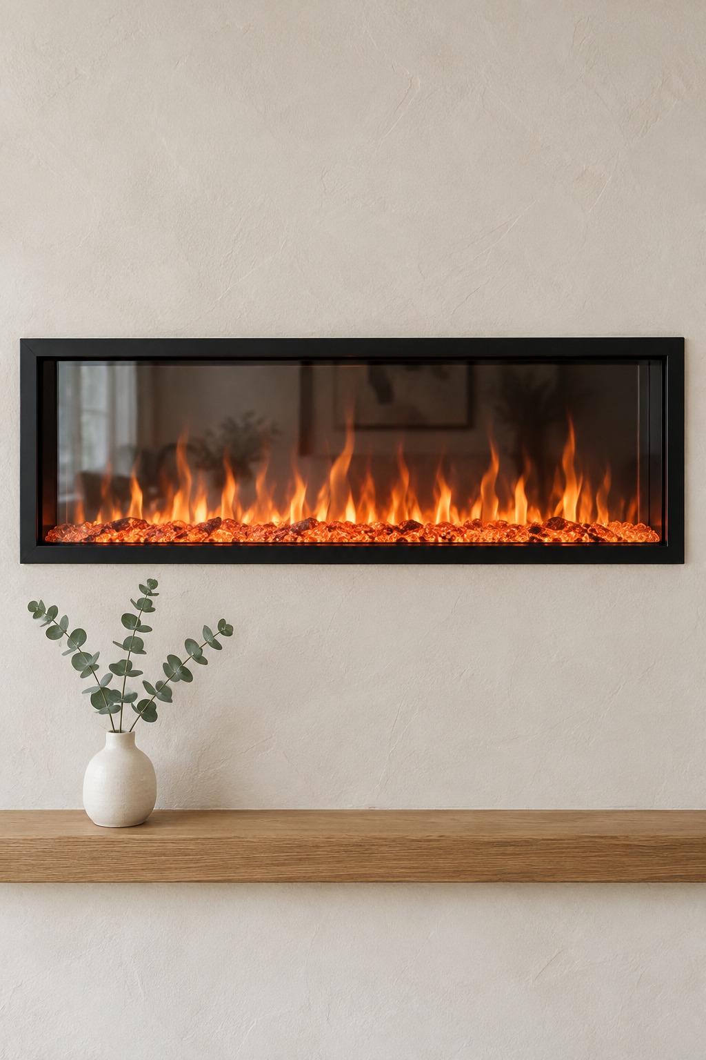 Close view of flames and ember bed behind glass in a slim black-framed electric fireplace on a plaster wall