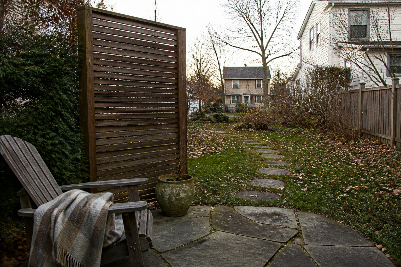 Late-fall patio chair beside a narrow slatted privacy screen with the walking path left open