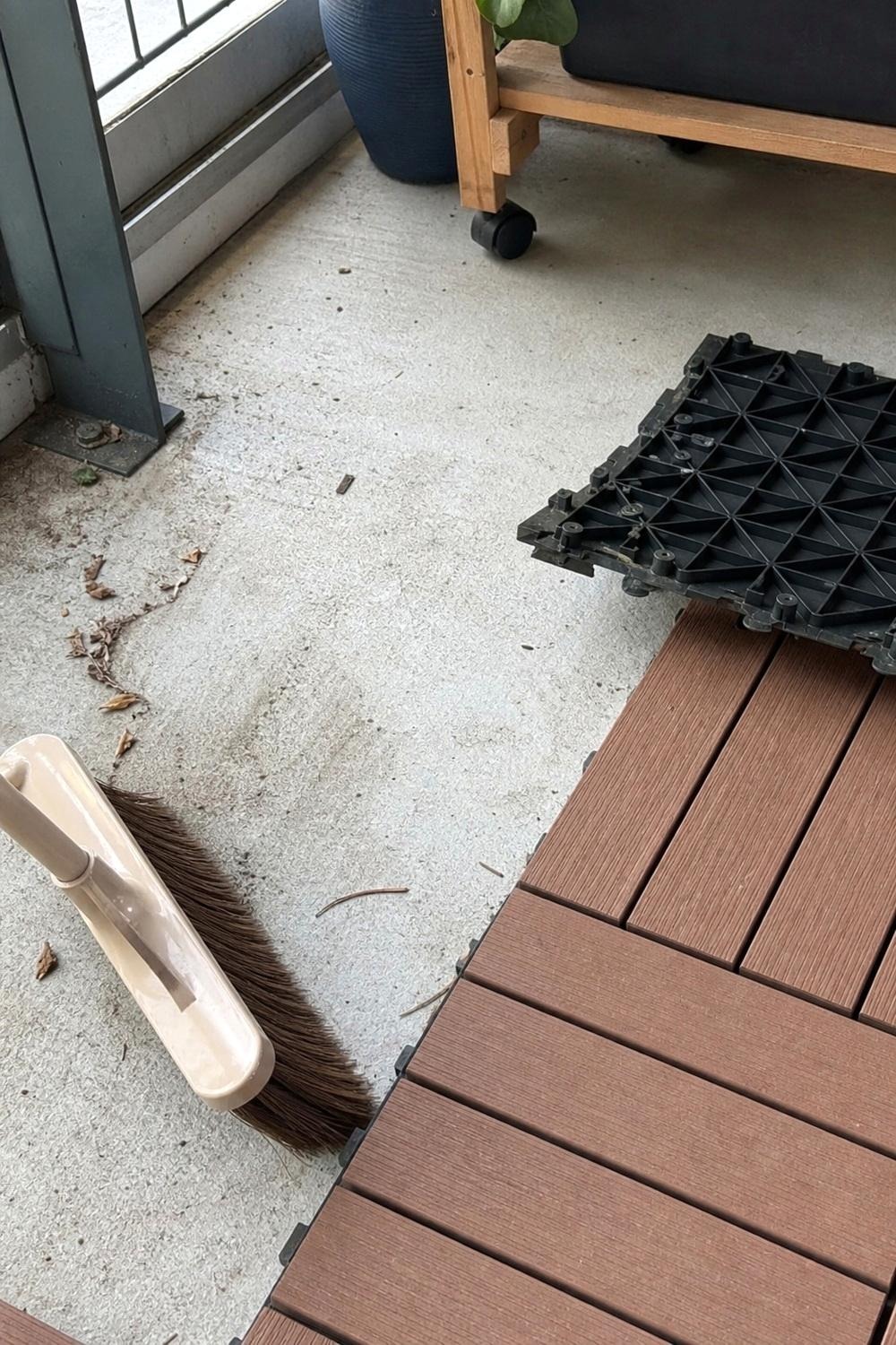 Outdoor polypropylene rug being rinsed clean with a hose on an apartment balcony