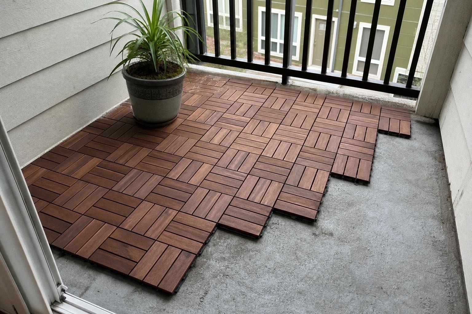Interlocking wood look deck tiles laid over a small concrete apartment balcony with two chairs