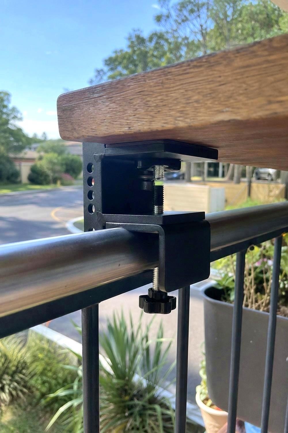 Close-up of a hook-on rail table lip gripping a flat balcony cap rail