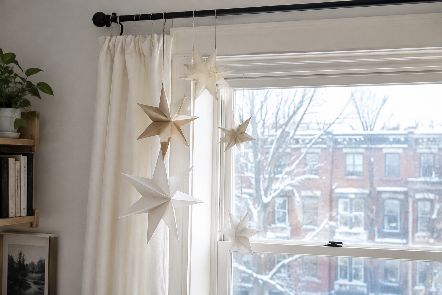 Paper stars hanging at different heights beside a small apartment window