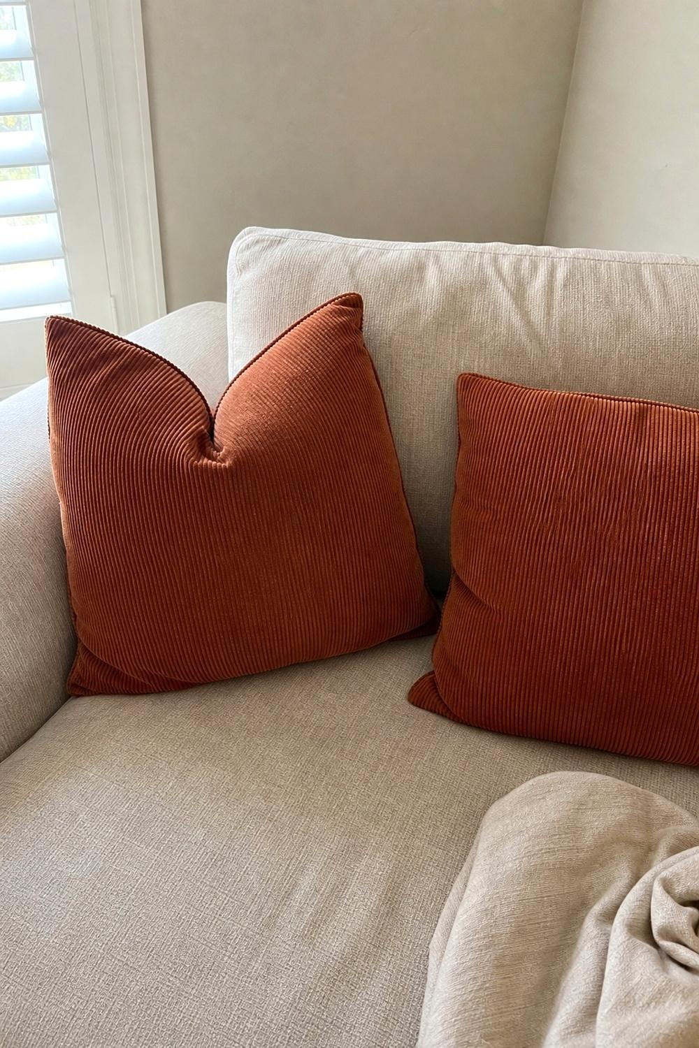 Rust corduroy throw pillow covers on a neutral sofa