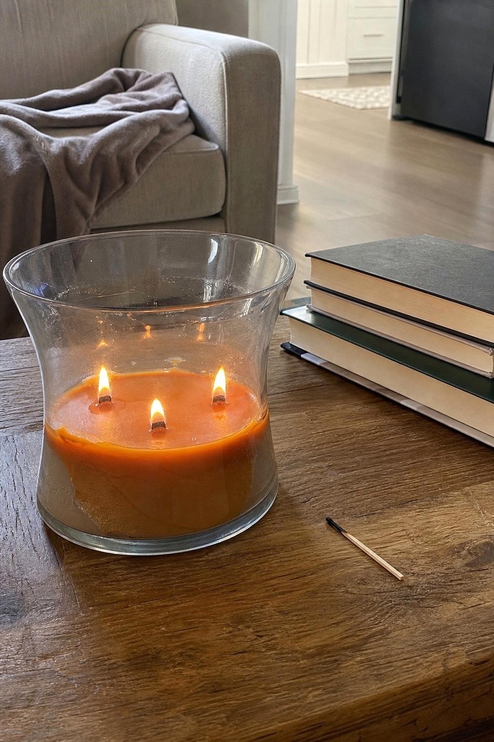 Wood wick autumn candle burning on a side table with warm light