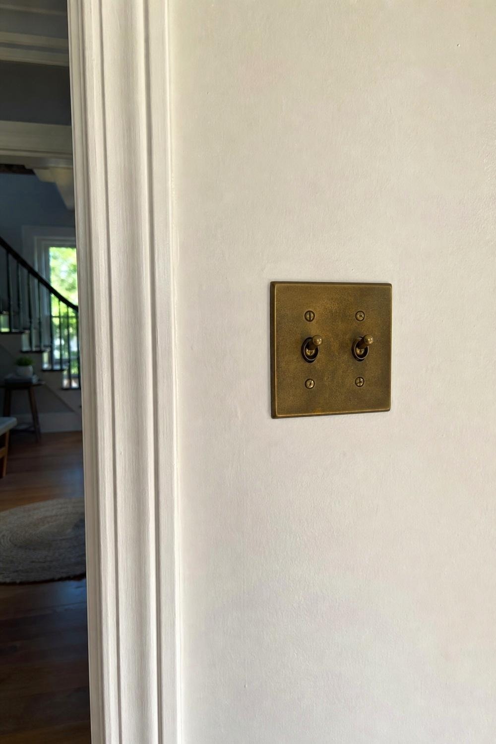 assortment of switch plate covers in brass, matte black, wood, and ceramic finishes on a table