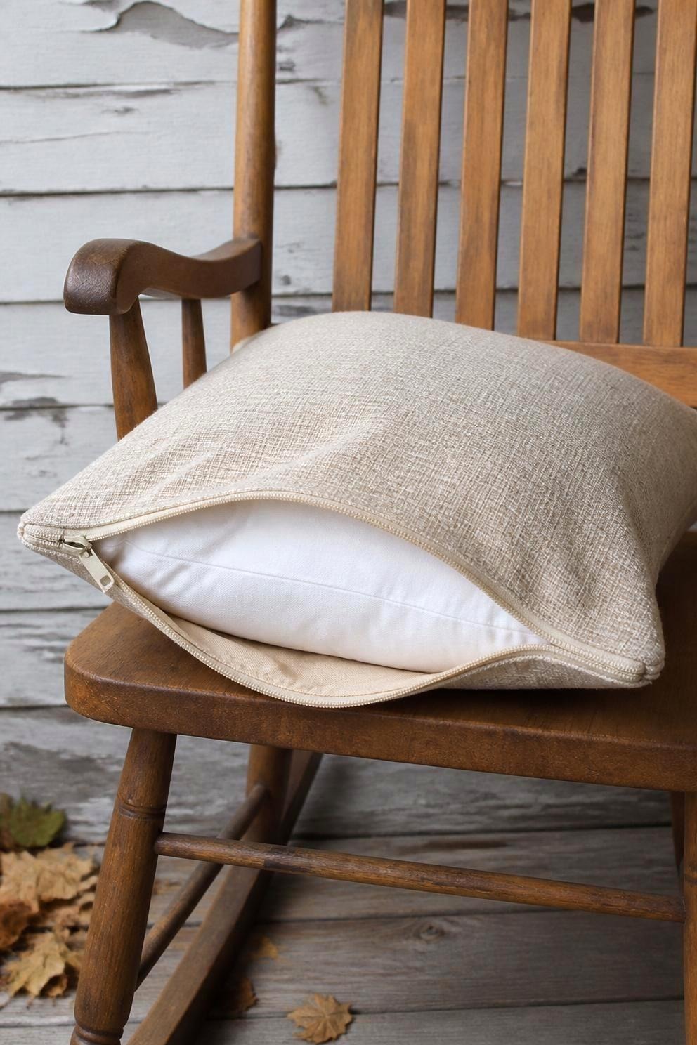 Close view of an unzipped outdoor pillow cover pulled partly back to show the white polyester insert inside