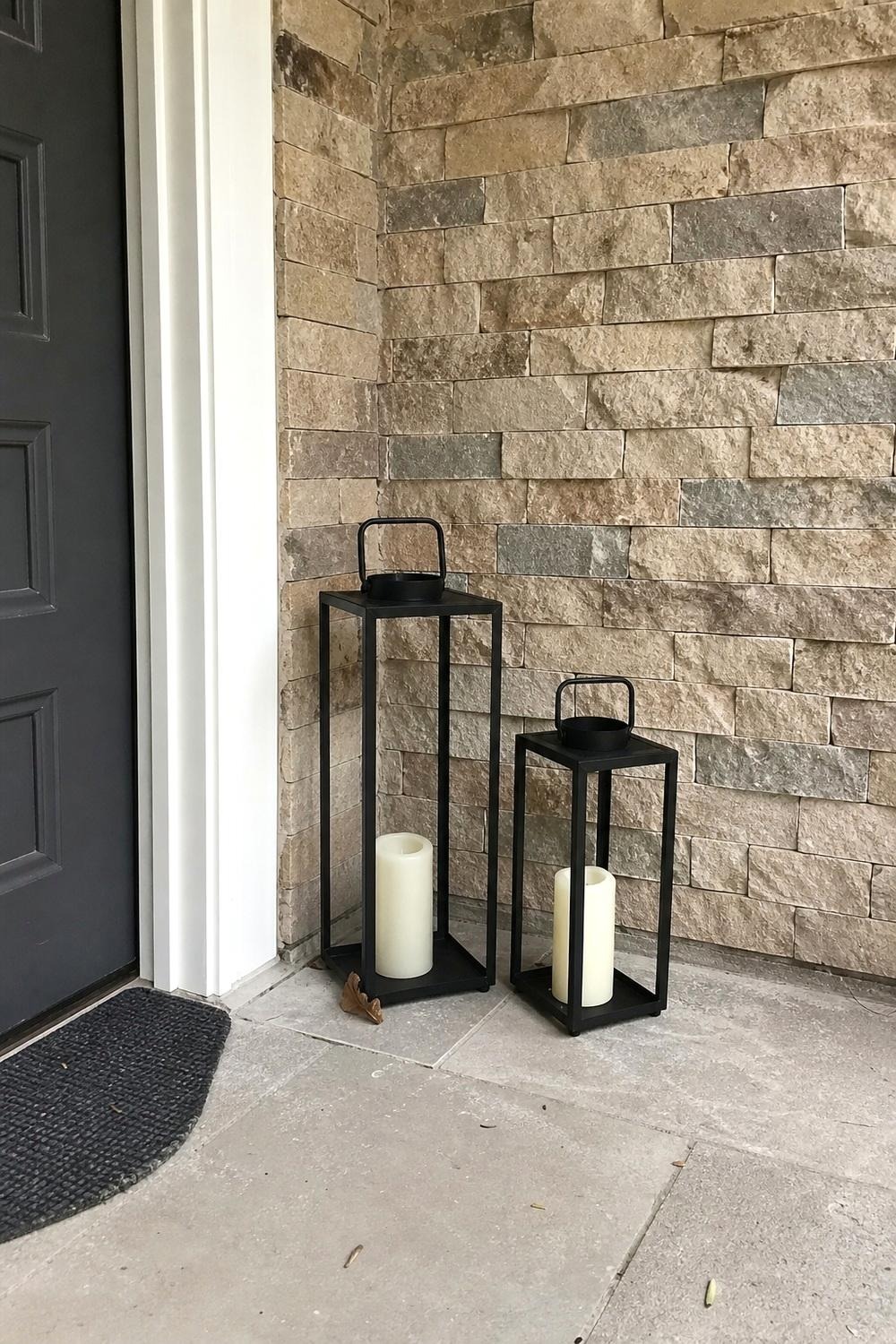 Two black metal floor lanterns of different heights flanking a covered porch entry