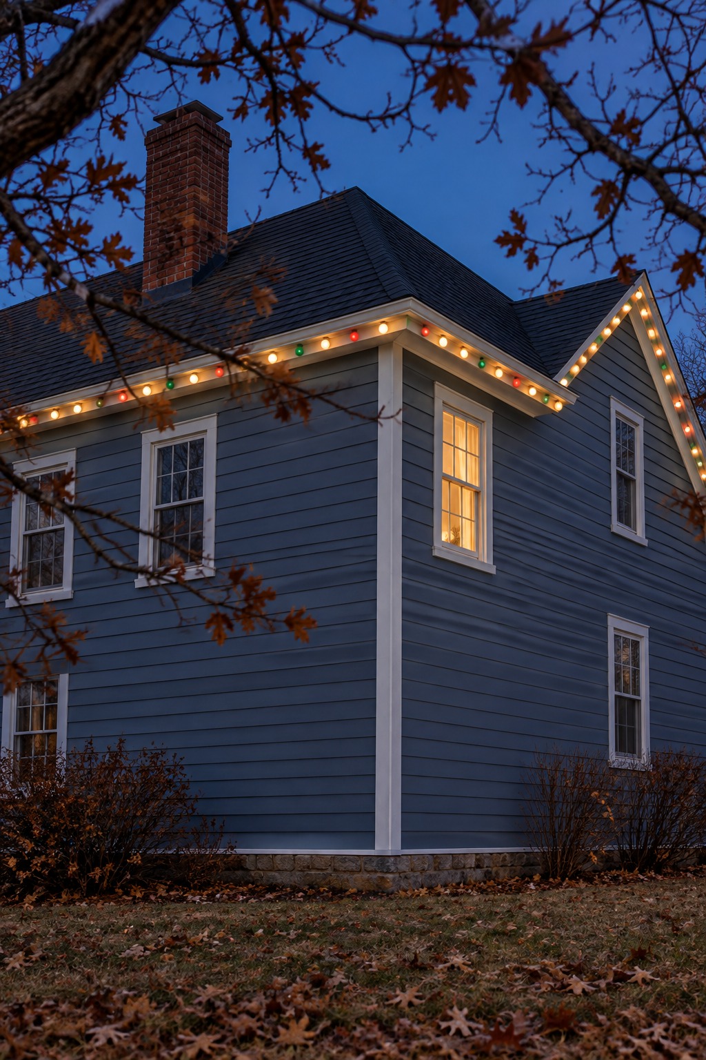 House corner at dusk with eave lights turning around the roof corner, mostly warm white with a few red and green