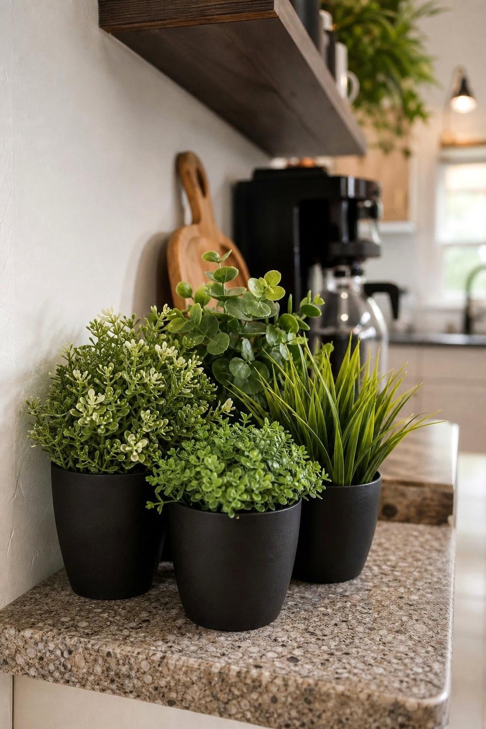 Small faux plants in black pots tucked between a mug rack and coffee canister on a Halloween-styled counter