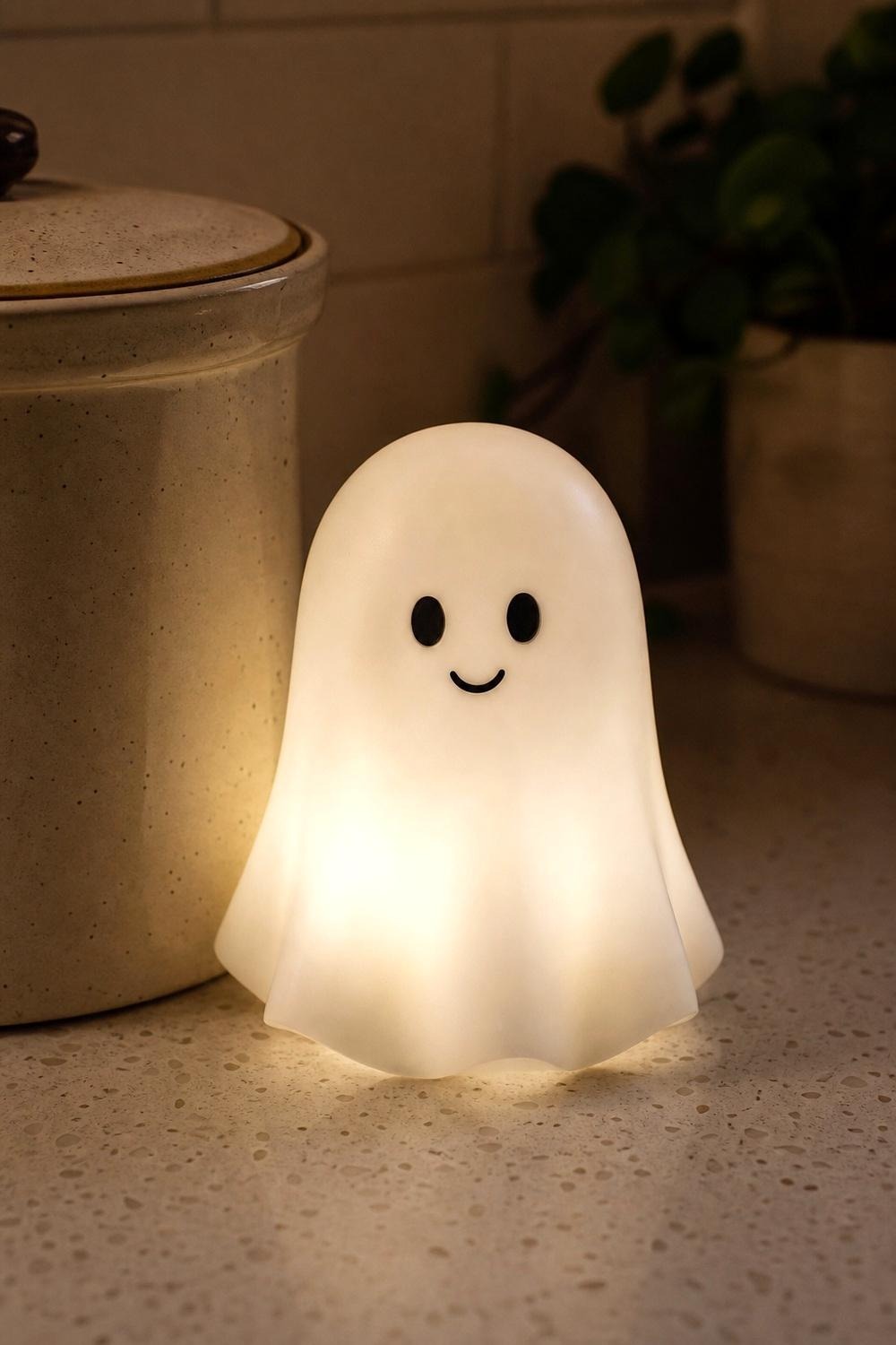 Small resin ghost figurine standing beside a stainless steel coffee canister on a kitchen counter