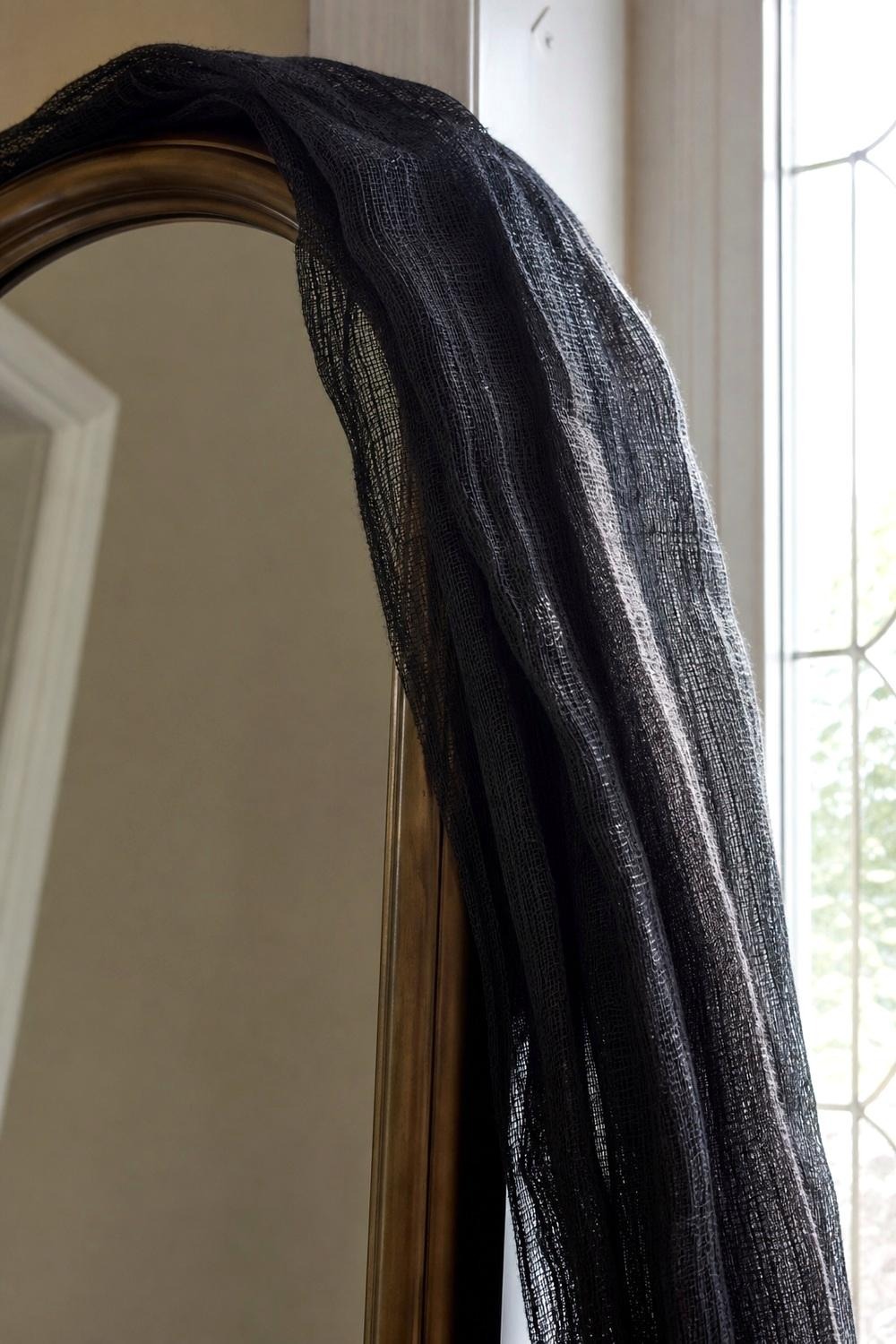 Sheer black creepy cloth draped over a stair rail near an entryway