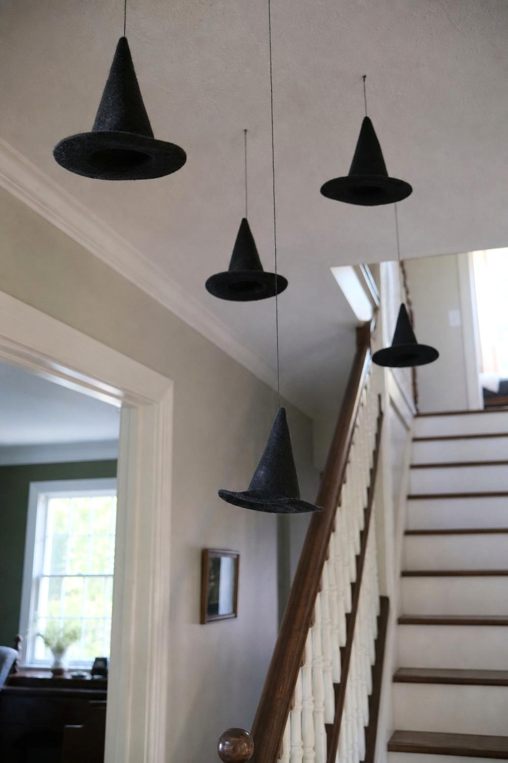 A cluster of black witch hats hanging from the ceiling above an entryway