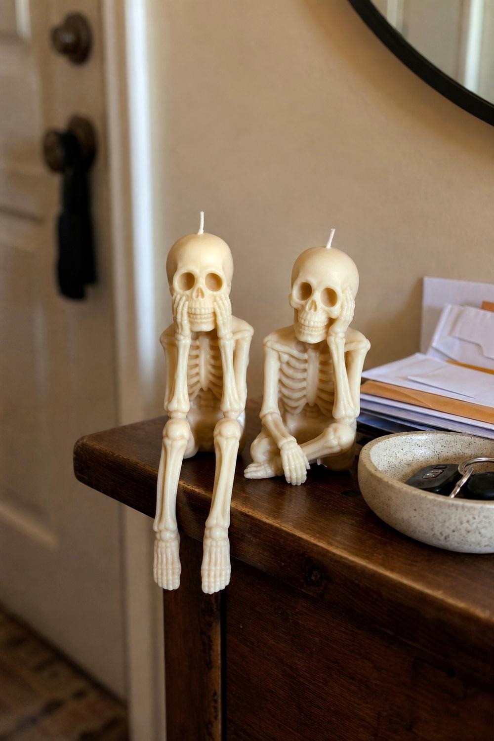 Cute skeleton-shaped candle decorations grouped on an entryway console table