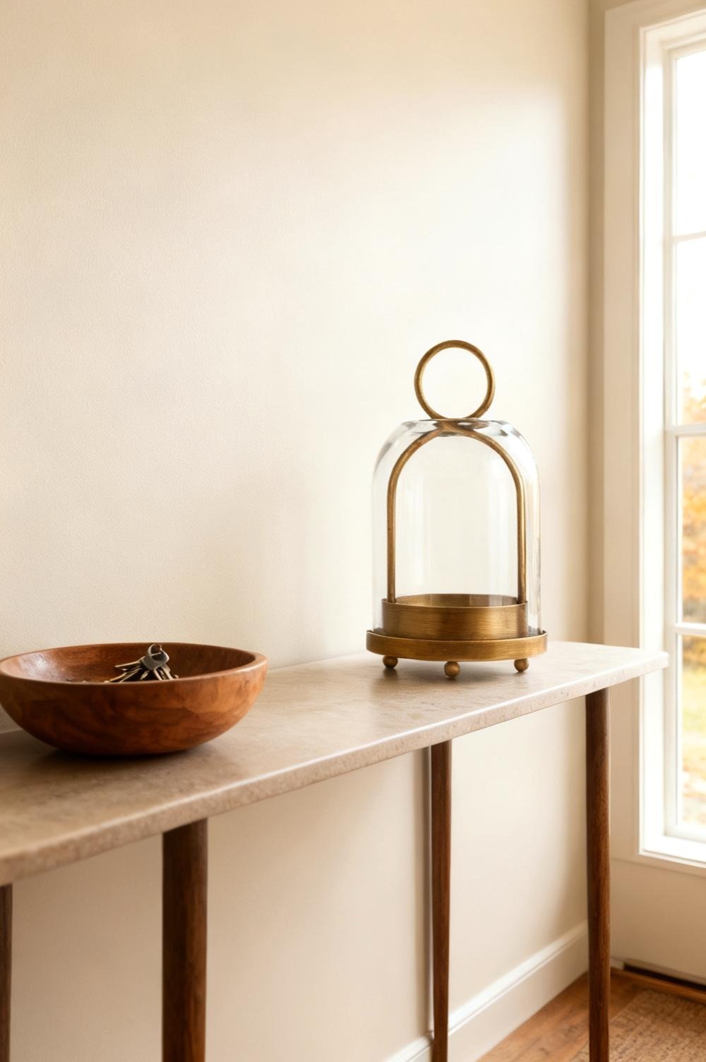 The Twakutwaku vintage brass hurricane lantern with its glass dome and ring handle on an entry console beside a bowl of keys