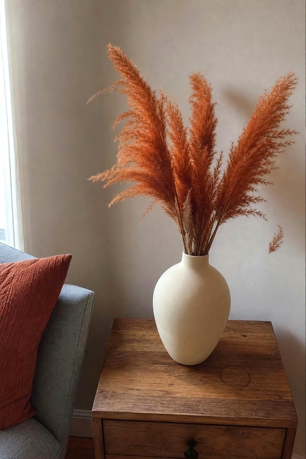 Burnt orange pampas grass stems in a plain ceramic vase