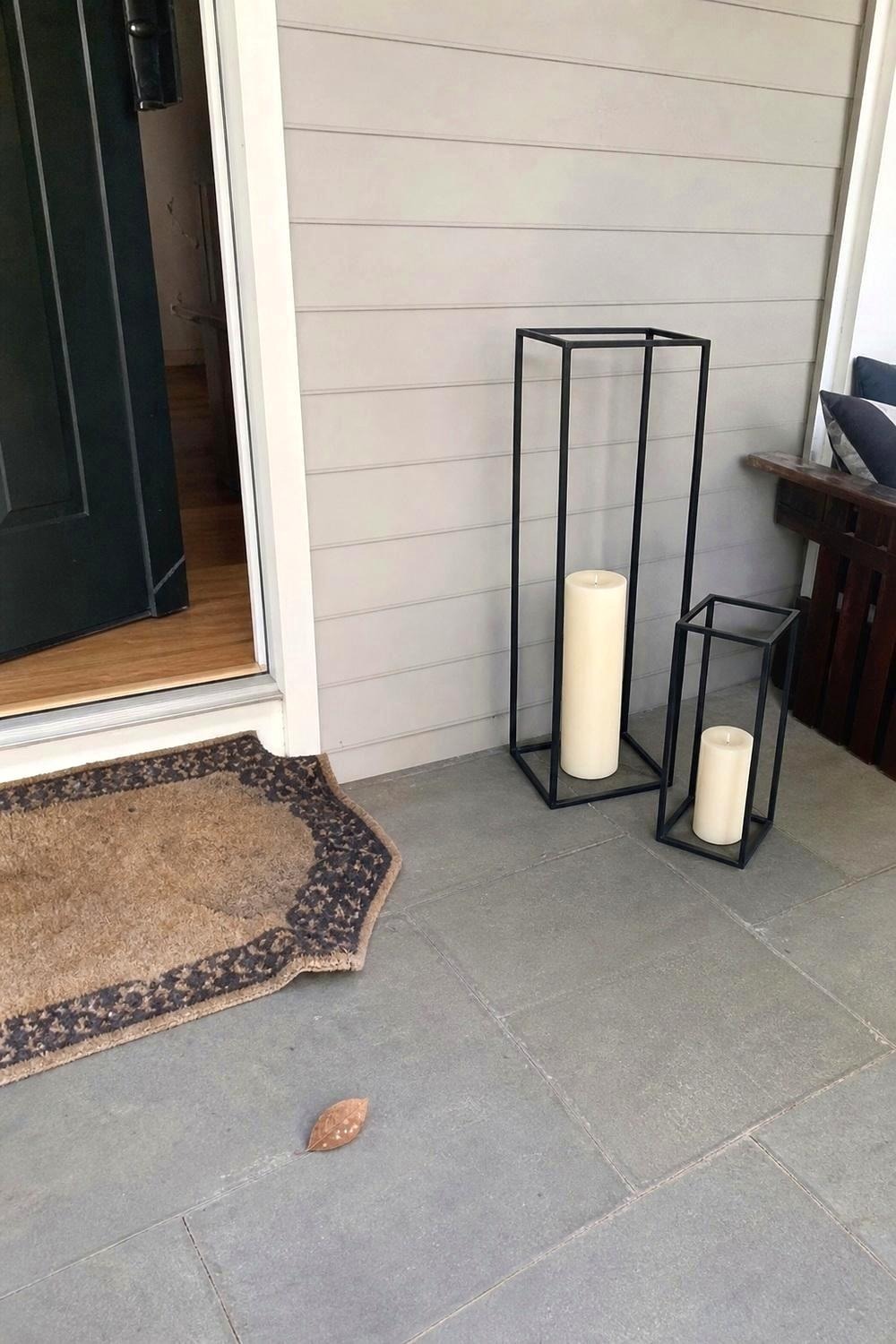 Two black metal candle lanterns of different heights beside a doorway