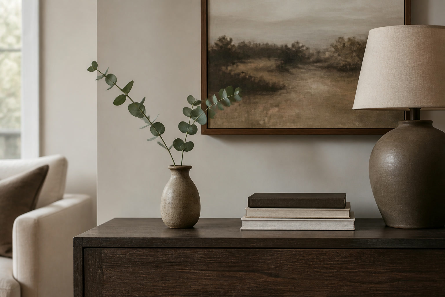 Small rustic ceramic vase on a dark wood console beneath framed art
