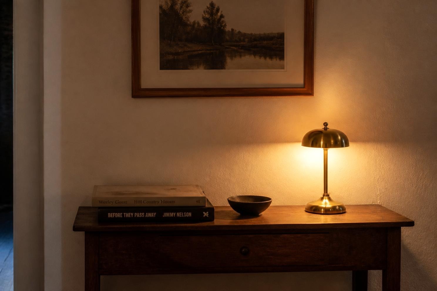 A small brass lamp lit on a console table against an interior wall