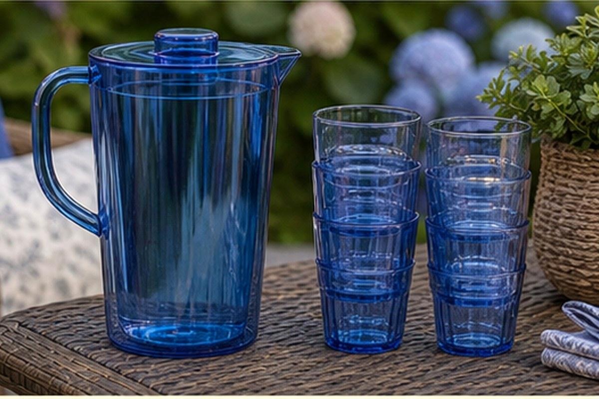 Blue acrylic pitcher with neatly stacked matching tumblers on a patio table