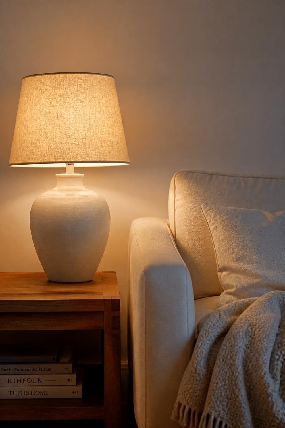 A living room lamp lit with a warm 2700K bulb beside a linen sofa in the evening