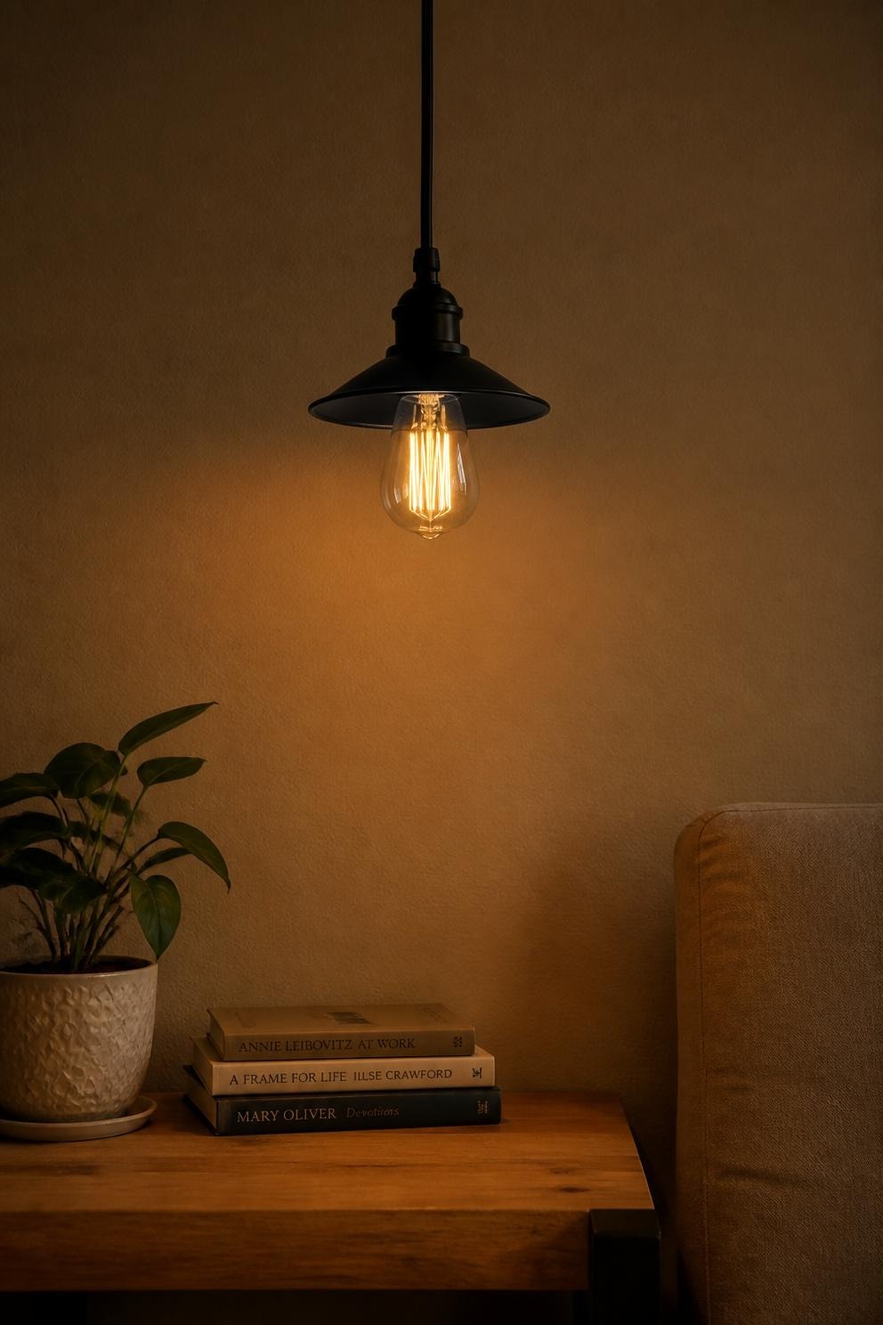 An exposed filament Edison bulb in an open pendant fixture above a side table